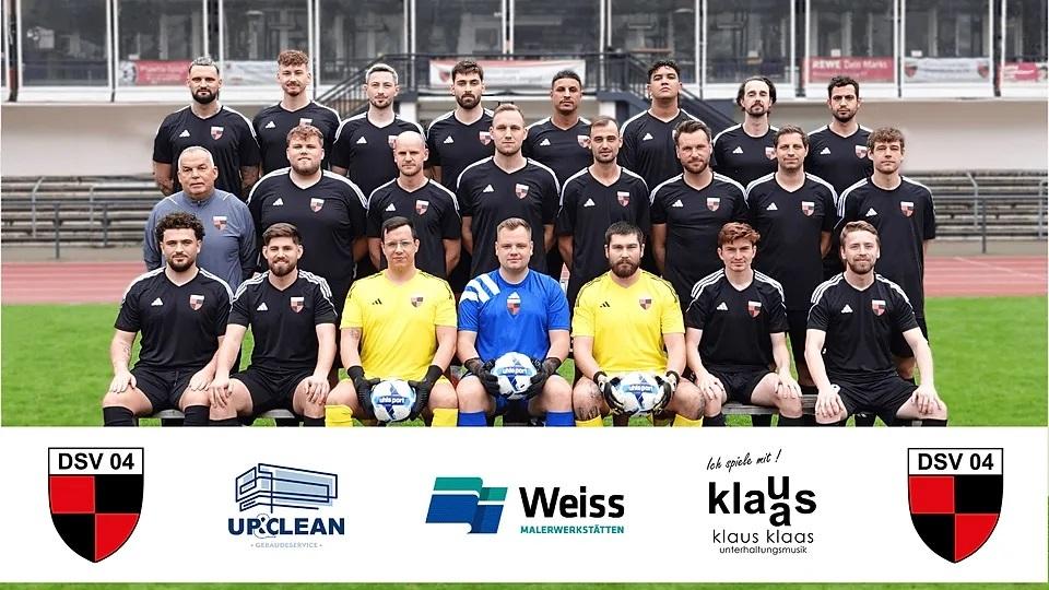 Mannschaftsbild des DSV 04 mit Spielern in schwarzen Trikots auf einem Fu&szlig;ballfeld, inklusive Torwart in gelbem Trikot.