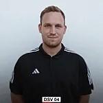 Portr&auml;t eines Mannes in einem schwarzen Adidas-Trikot vor einem hellen Hintergrund.