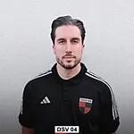 Portr&auml;t eines Mannes mit kurzen Haaren in einem schwarzen Adidas-Trikot mit Logo auf einem einfarbigen Hintergrund.