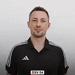 Portr&auml;t eines Mannes mit kurzem Haar, schwarz-wei&szlig;er Sportbekleidung und neutralem Ausdruck vor einem hellen Hintergrund.