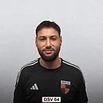 Sportler in schwarzem Trikot mit Logo, vor grauem Hintergrund, l&auml;chelt in die Kamera.