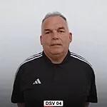 Mann in schwarzem Sportoberteil mit wei&szlig;en Streifen, stehend vor neutralem Hintergrund.