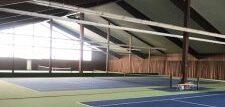 Sporthalle mit mehreren Tennispl&auml;tzen in Gr&uuml;n und Blau, helle Fenster sorgen f&uuml;r nat&uuml;rliche Beleuchtung.