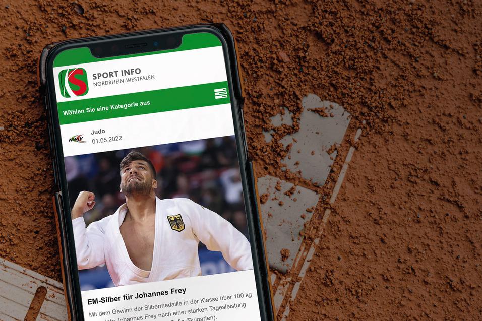 Smartphone liegt auf rotem Sportplatz, zeigt Artikel &uuml;ber Johannes Frey und EM-Silbermedaille.